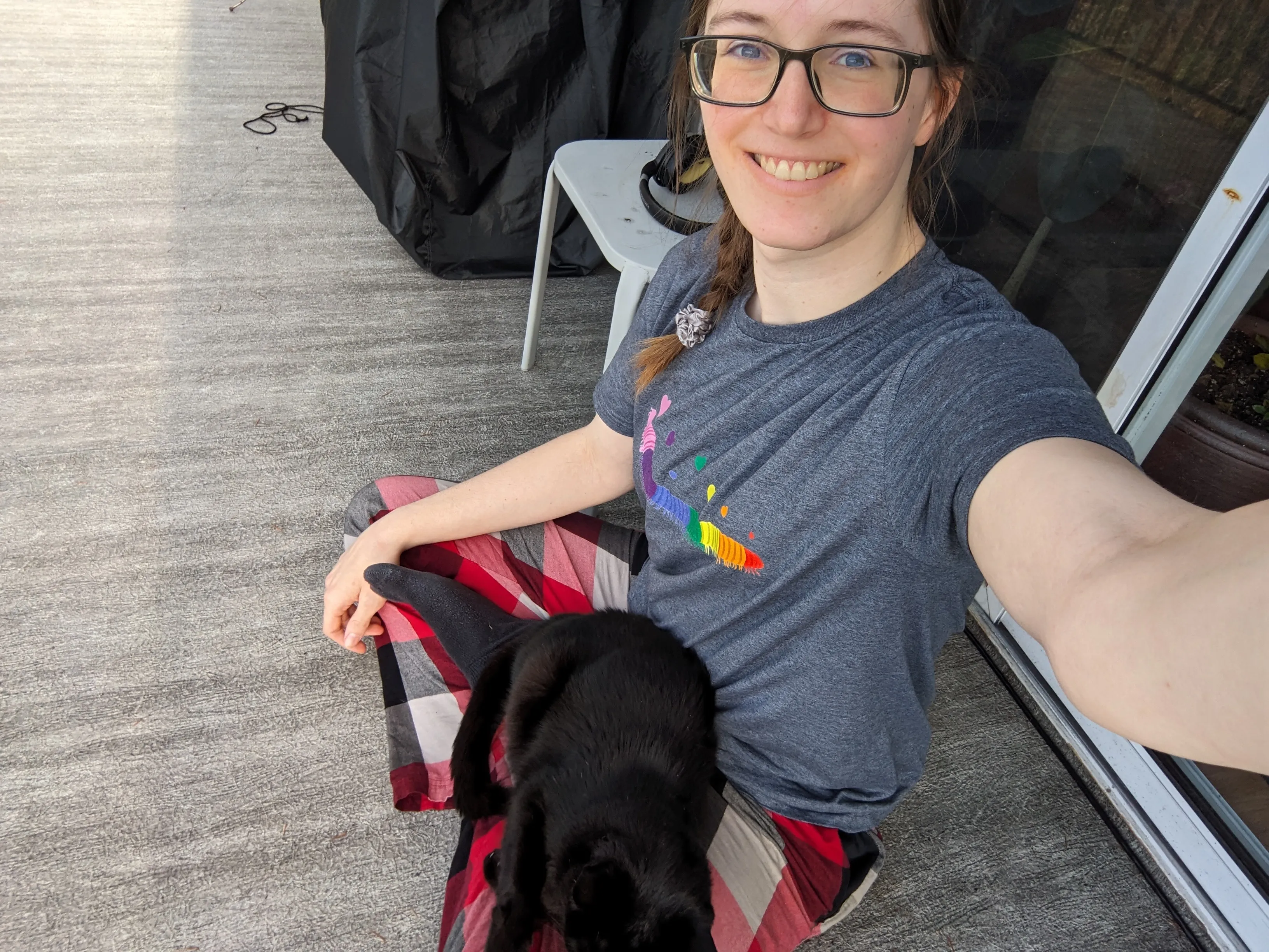 Katherine takes a selfie while sitting outside with her neighbours' cat on her lap.