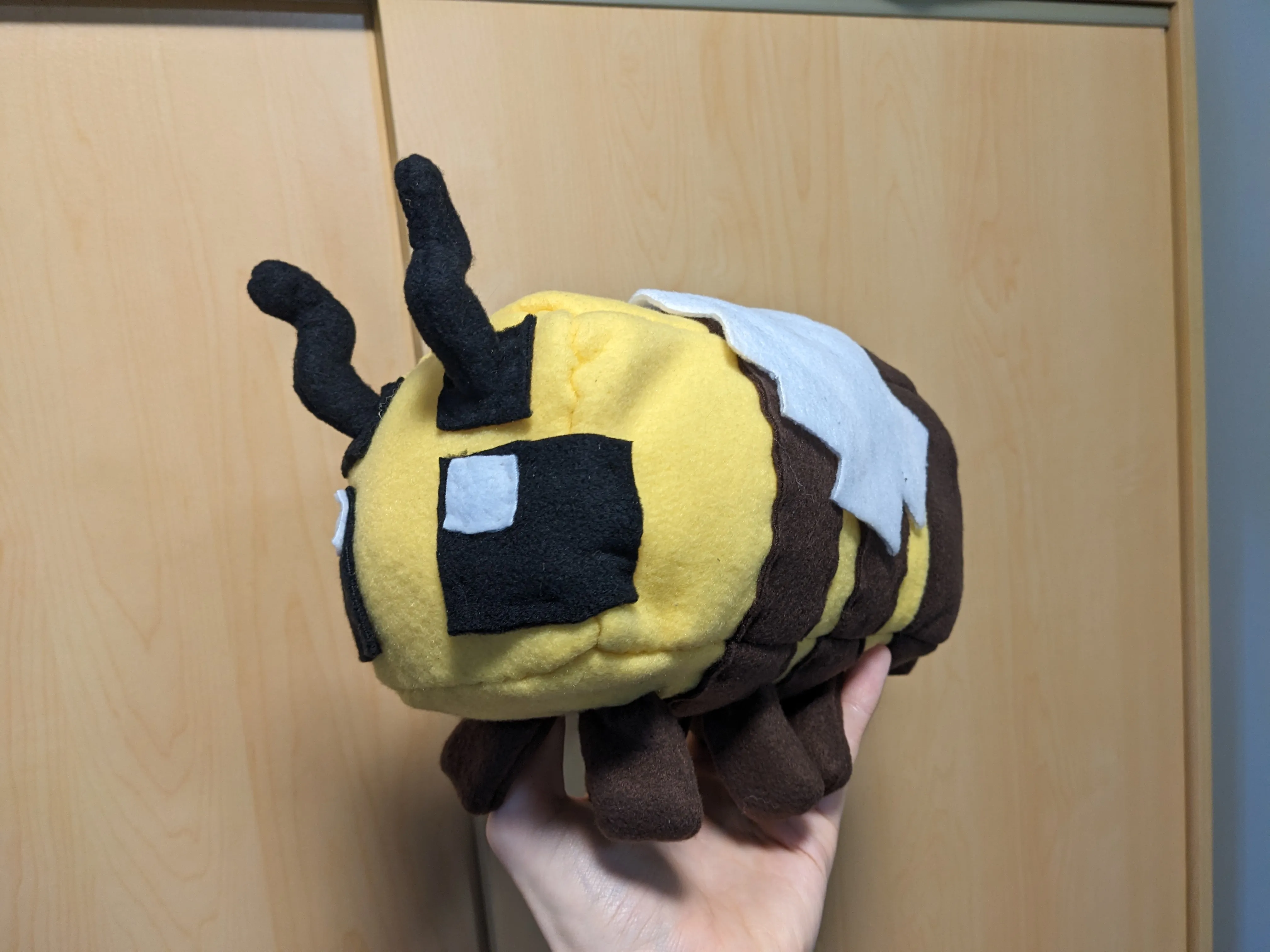 my hand holding my pushie minecraft bee