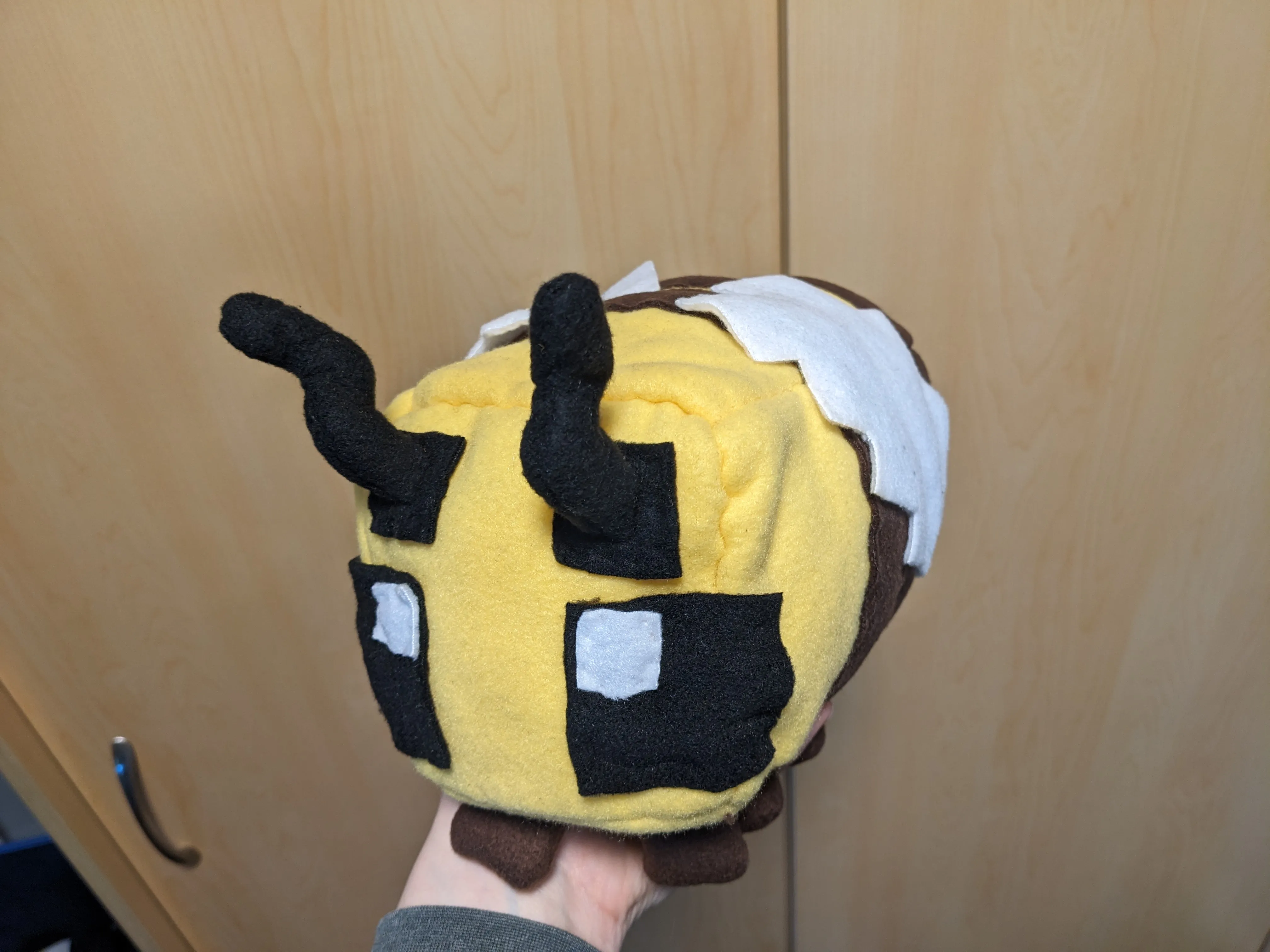 my hand holding my pushie minecraft bee at another angle